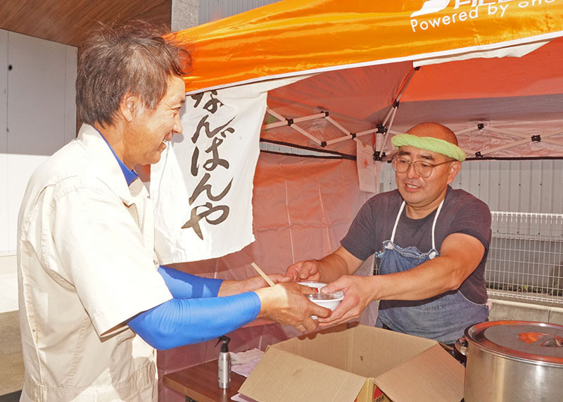 駐車場の一角で来店者（左）に飲食物を販売する出店事業者＝1日、北上市・北上信金柳原支店