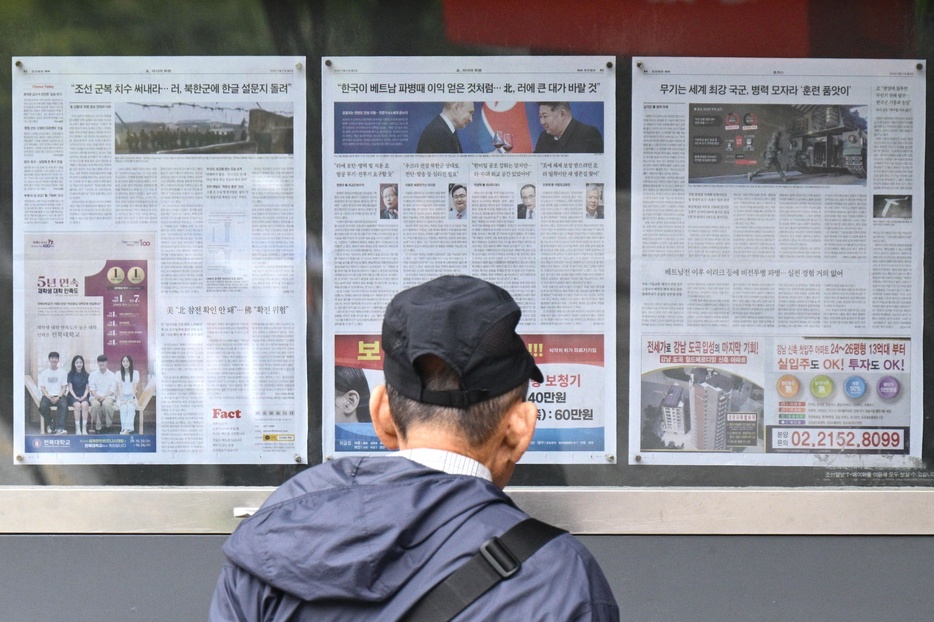 韓国ソウル市の街頭で、北朝鮮軍によるウクライナ紛争への派兵決定に関する報道を読む男性（2024年10月21日撮影）。【翻訳編集】 AFPBB News