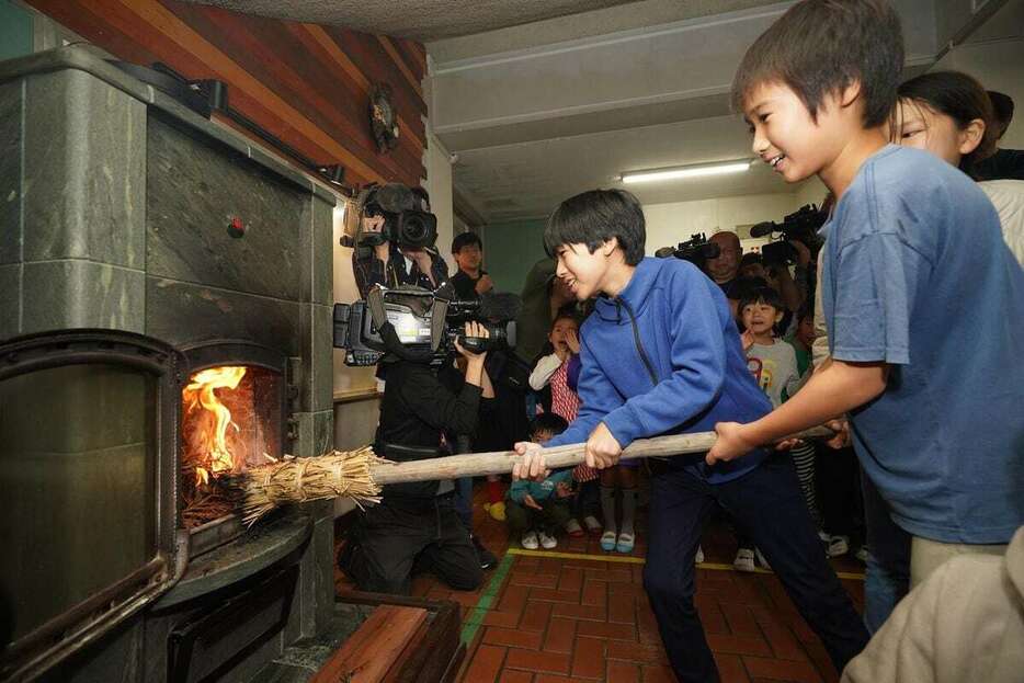 起こした火種をストーブに入れる児童たち＝23日午前、神戸市灘区の六甲山小学校（南雲都撮影）