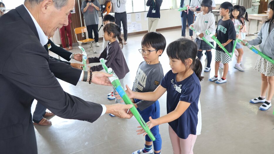 緑色の雨傘を受け取る竜王小の児童たち（竜王町綾戸・竜王小）