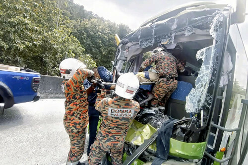 トラックの後部に衝突した観光バスから運び出される負傷者（２４日、マレーシア西部ペラで）＝ＡＰ