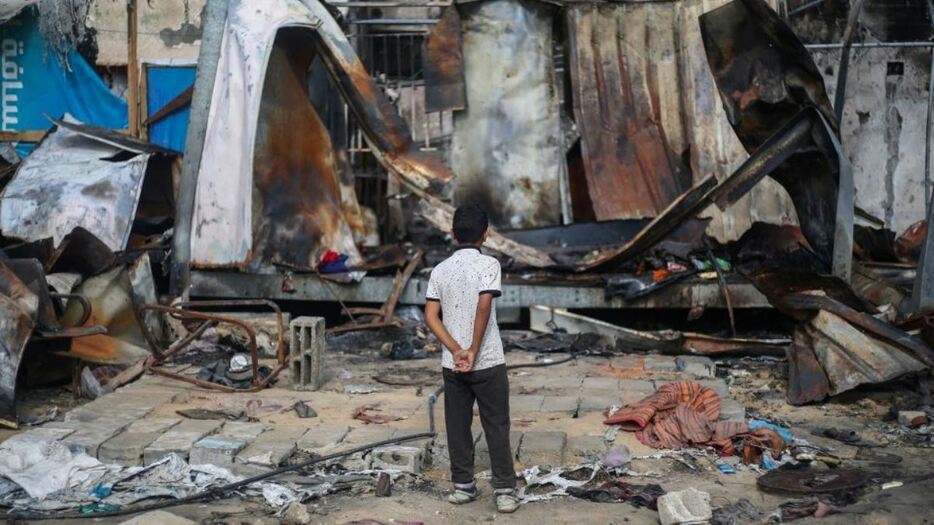 ガザ中部にある病院の中庭でイスラエルの空爆により破壊された避難所を見つめる少年