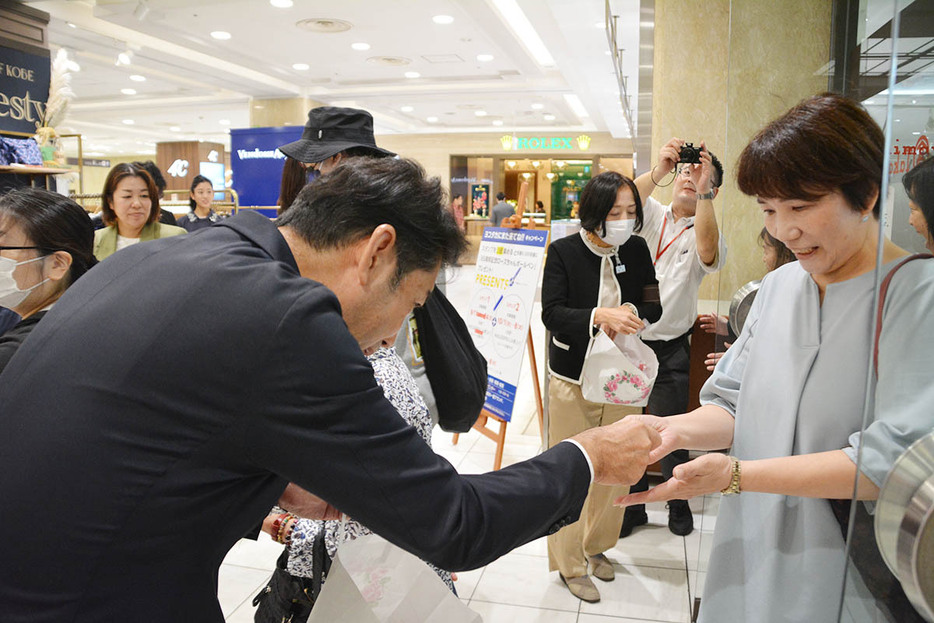 来店者にあめを配布する竹下店長（左）＝横浜市西区の横浜高島屋