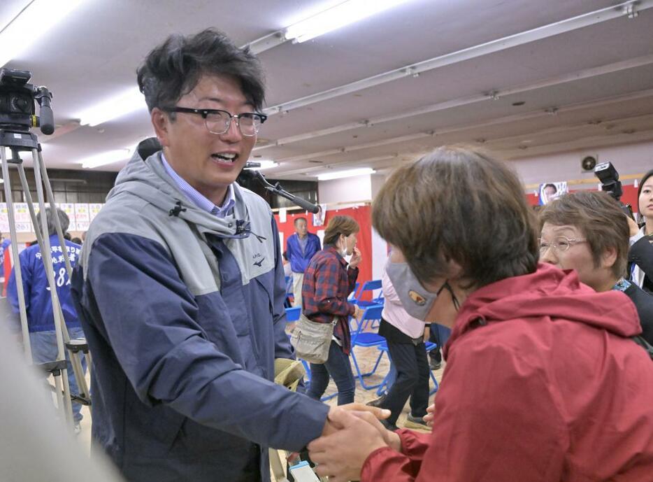 小選挙区で初当選を決め、支持者と握手を交わす中村勇太氏(左)=27日午後10時52分、古河市下辺見、鈴木葵撮影