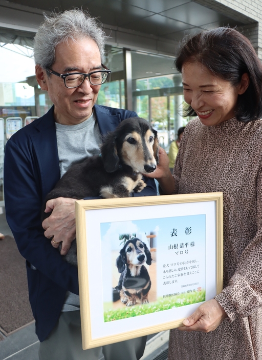 長寿犬表彰を受けた「マロ」と飼い主の恭平さん、朋代さん＝2024年10月16日午後2時6分、兵庫県丹波市山南町谷川で