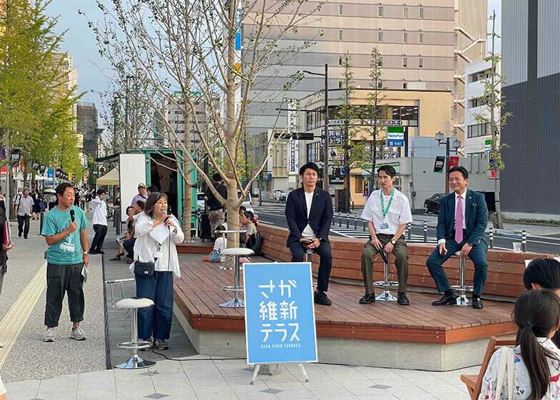 平常時はベンチとして使われているステージ。青空の下、佐賀のまちと車道を背景にトークセッションが行われた（写真撮影／唐松奈津子）