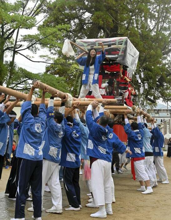 約40人の男性がさし上げる四ツ太鼓の上に立ち、ガッツポーズで会場を盛り上げた井上さん（中央）