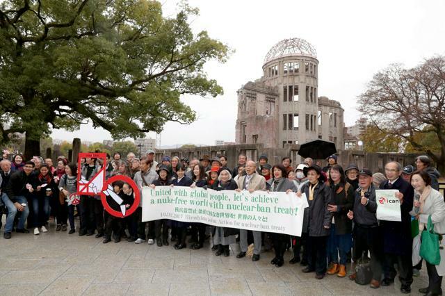 ICANのノーベル平和賞受賞を祝い、原爆ドーム前で横断幕を掲げる市民集会の参加者たち=2017年12月10日、広島市中区、上田幸一撮影