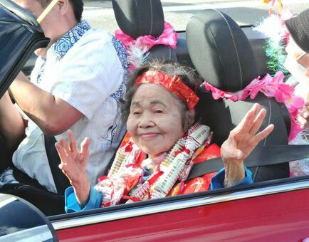 カジマヤーパレードのオープンカーに乗ってカチャーシーを踊る山城スミさん＝１３日、うるま市石川山城