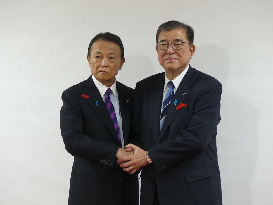 麻生太郎最高顧問（左）に衆院選の公認証を手渡した後、握手で写真撮影に応じる石破茂首相（撮影・中山知子）