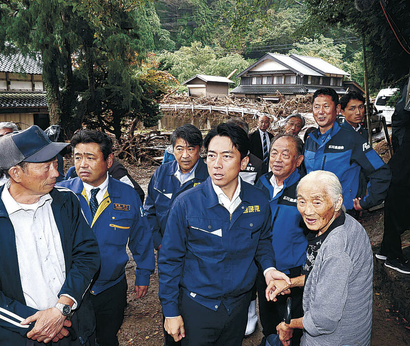 大規模な土砂災害の発生現場で被災した高齢者の手を取る小泉氏＝能登町北河内