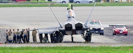 タイヤが破裂して緊急停止したＦ２２ステルス戦闘機の後部左側を点検する隊員ら＝１８日午後１時２０分、米軍嘉手納基地