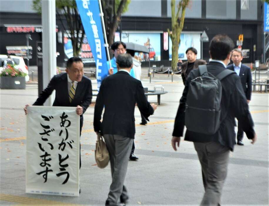 「ありがとうございます」の看板をもって当選御礼あいさつする中島克仁氏＝28日、甲府市（平尾孝撮影）