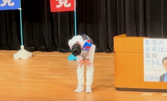 公明党の集会で頭を下げる西村康稔氏（提供写真）