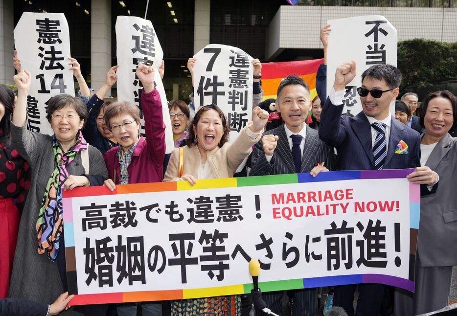 同性婚を巡る東京第1次訴訟の控訴審判決を受け、「高裁でも違憲」などと書かれた横断幕を掲げる原告ら＝30日午前、東京高裁前