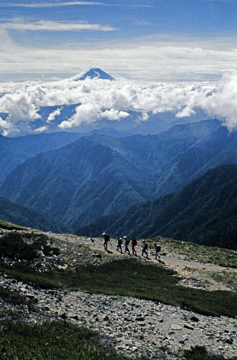 富士山（中央奥）を望みながら、南アルプスの北岳山頂を目指す登山パーティー（1987年8月、山梨県）　©時事通信社