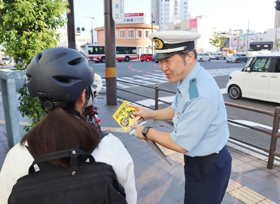 街頭でチラシを配る県警交通企画課の警察官＝大分市高砂町