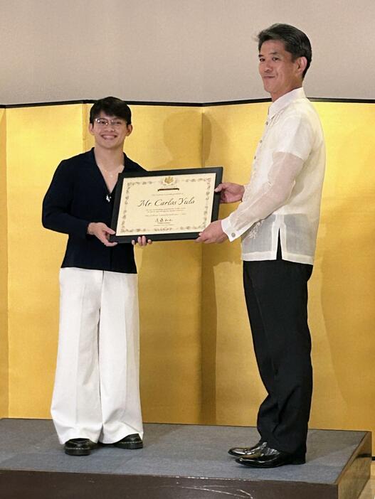 1日、マニラの日本大使公邸で、遠藤和也大使（右）から大使特別賞を受けるカルロスエドリエル・ユーロ選手（共同）