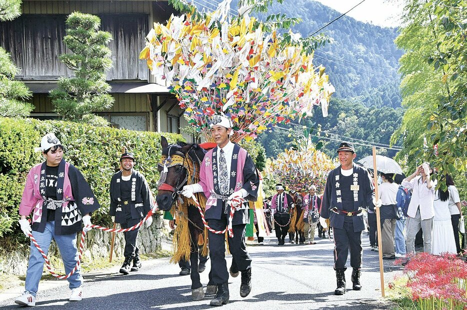 花飾りを背負った木曽馬などの行列がにぎやかに地域を練った祭り