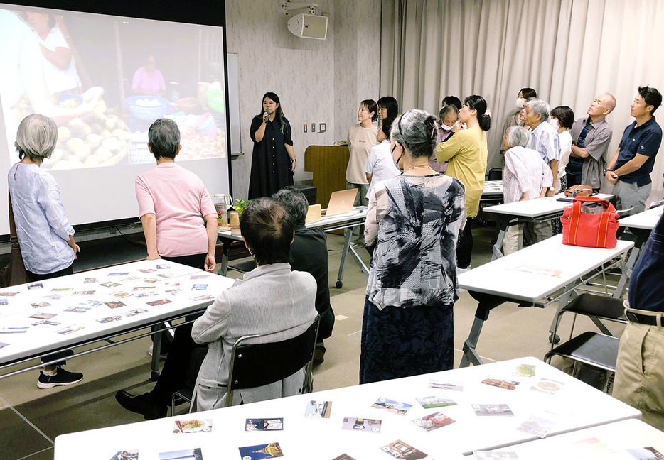 現地の人たちや生活を伝えるかるたを交えて話す野中さん（真ん中）＝本町の市産業振興センターで