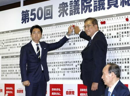 当選を決めた自民党の小泉選対委員長（左）の名前にバラを付ける総裁の石破首相＝27日午後9時45分、東京・永田町の党本部