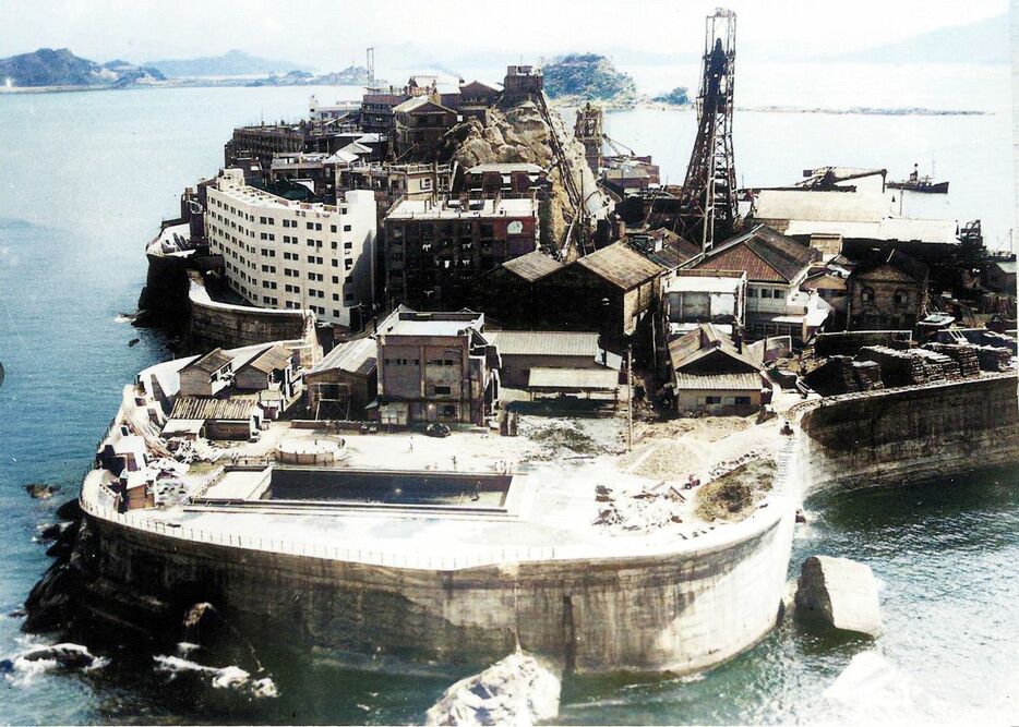 1958年（昭和33）ごろ、南側から俯瞰した端島。左側の白い建物は31号棟。その右となりは30号棟で、新築まもない時期　写真＝『カラーでよみがえる軍艦島』より - 提供＝軍艦島デジタルミュージアム