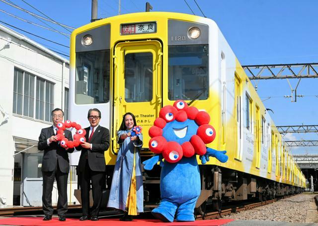 完成したラッピング電車と河瀬直美さん（左から3人目）ら=2024年10月17日午前10時24分、奈良市尼辻北町、佐藤道隆撮影