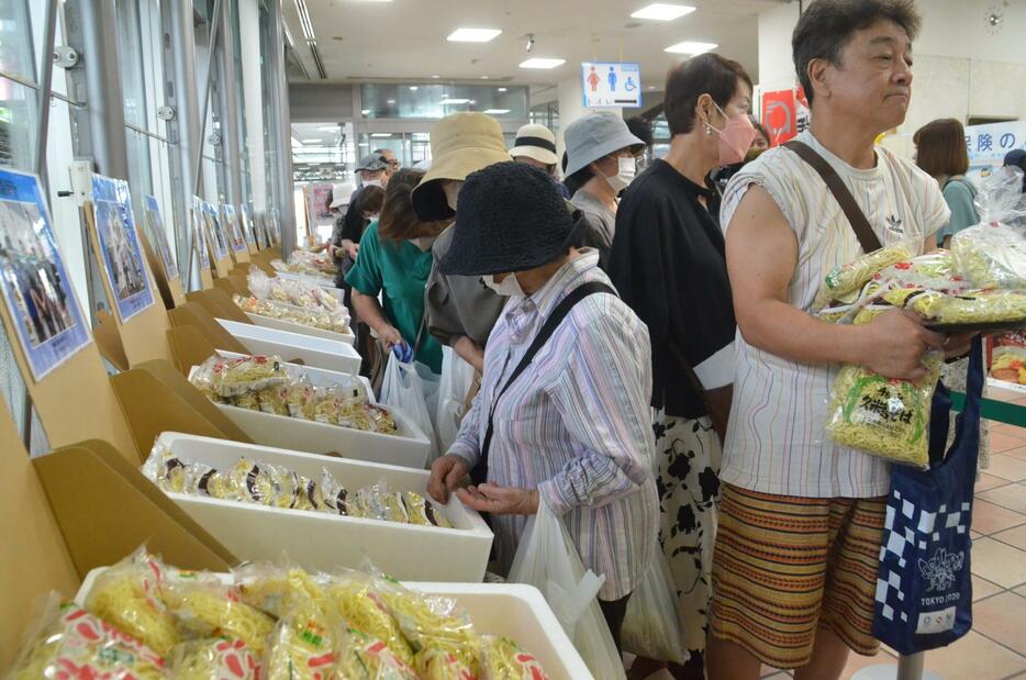 17種の沖縄そばがずらりと並んだ売り場で買い物を楽しむ来場者＝16日、那覇中央郵便局