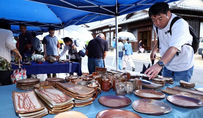 雨の中、歩行者天国の通りで品定めする来場者