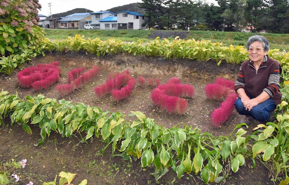 コキアで作った「ありがとう」の横で笑顔を見せる神さん