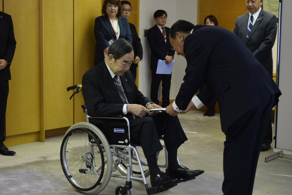 車いすに乗ったまま辞職届を提出する岩倉市長（左）＝28日午後１時半ごろ、苫小牧市役所