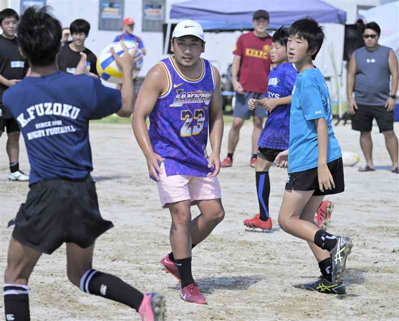 中学生にラグビーの指導をする流大選手（中央）＝9月14日、荒尾市