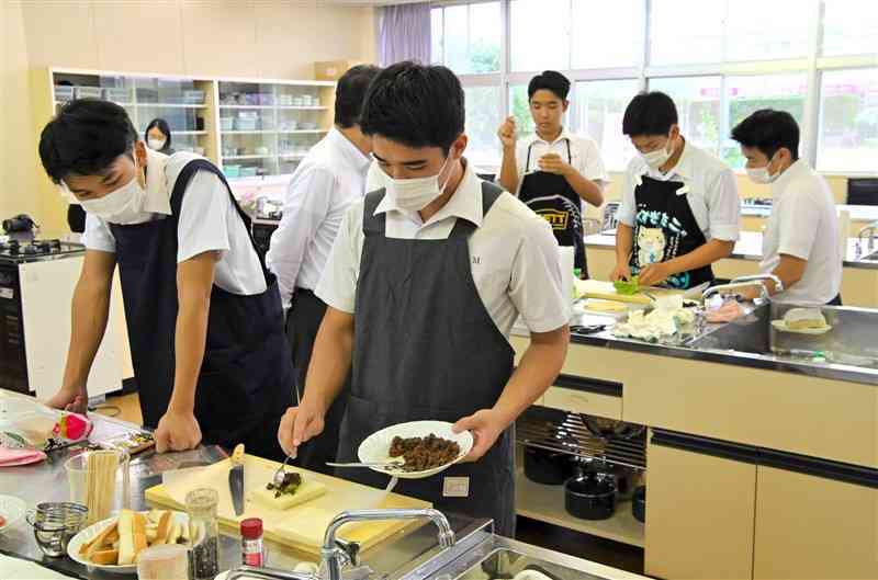 シカ肉のホットサンドとブリトーを真剣な表情で試作する八代工高の生徒ら＝25日、八代市