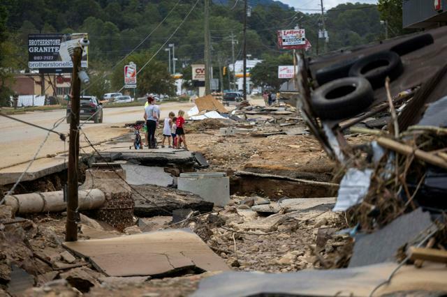 2024年9月29日、大型ハリケーン「ヘリーン」により壊滅的な洪水被害が出た米ノースカロライナ州西部を歩く人たち=ロイター