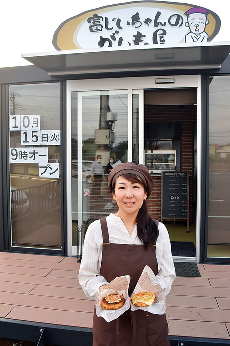 15日にオープンする店舗の前で、深谷ねぎがんも（お好み焼き風）と玉ねぎがんも（チーズのせ）を持つ店長の冨岡美紀さん＝深谷市深谷の「富じいちゃんのがんも屋」