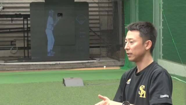 今年導入した「トラジェクトアーク」(奥のマシン）について説明する球団スタッフの城所収二さん