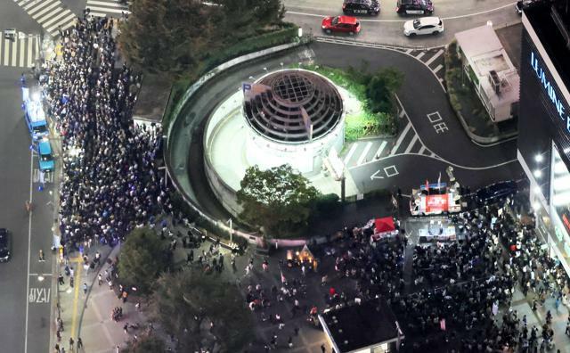 衆院選投開票日の前日、党首や候補者の街頭演説に集まった人たち。2陣営が鉢合わせしている=2024年10月26日午後7時21分、都内、朝日新聞社ヘリから、嶋田達也撮影（選挙カーにモザイクをかけています）