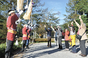 木落し坂の上で木やりを聞き、御柱祭へのイメージを膨らませたツアー客＝下諏訪町萩倉