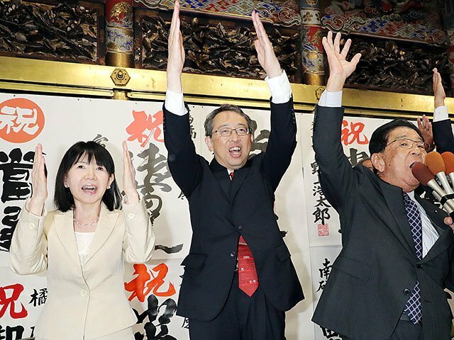 選対総括責任者の米原県議の主唱で万歳する橘氏（中央）と妻のカオルさん（左）＝２７日午後９時５分ごろ、高岡市中川の事務所