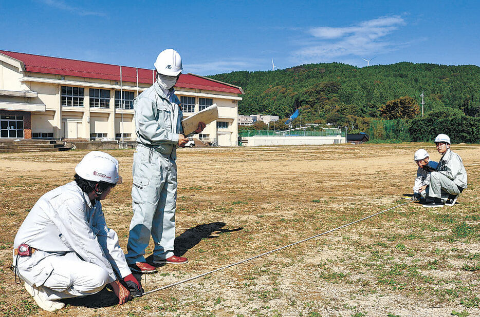 仮設住宅の建設に向け配置を確認する作業員＝１８日午前１０時２５分、輪島市門前東小