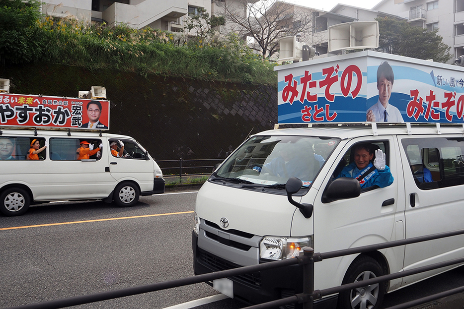 大票田の鹿児島市谷山地区で交差した三反園訓氏の選挙カー（手前）と保岡宏武氏の選挙カー