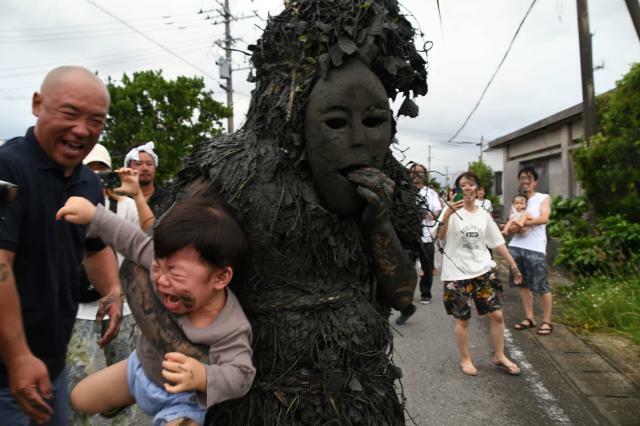 パーントゥに抱きかかえられて泣き叫ぶ幼児＝8日、平良島尻