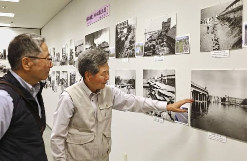 展覧会で、来場者（左）に写真の説明をする近藤武夫さん＝２０２４年６月、新潟市