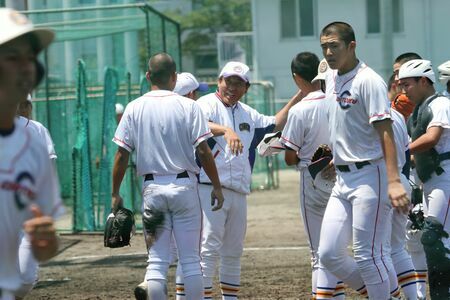 選手と笑顔で言葉を交わす初鹿文彦監督（山梨・甲府城西高校との練習試合前）