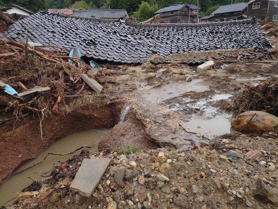 地震で崩れた建物に、水害で流れた流木が重なり合う（9月26日撮影）