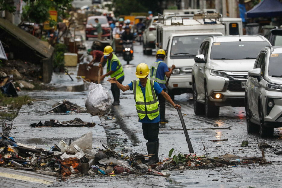 フィリピンのルソン島を２４日、台風２０号が横断し、各地で洪水や土砂崩れが発生した。地元当局によると、少なくとも２５人の死亡が確認された。写真はケソン市で、洪水によるごみやがれきを集める作業員ら。