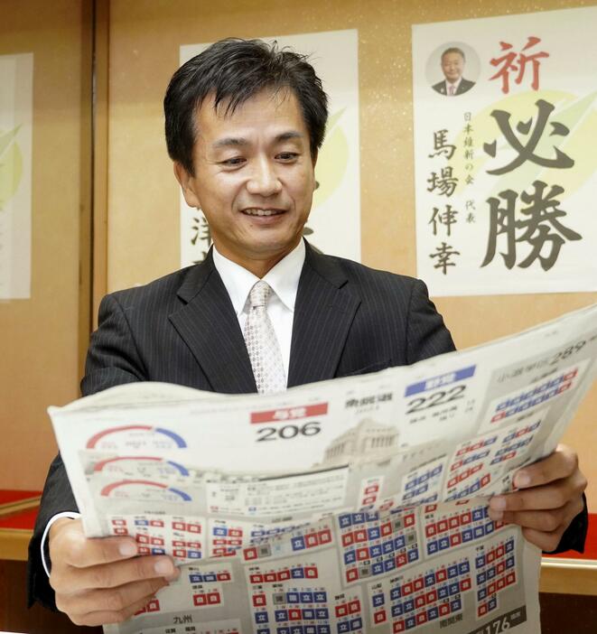 衆院福岡11区で初当選し、新聞に目を通す日本維新の会の村上智信氏＝28日午前、福岡県行橋市