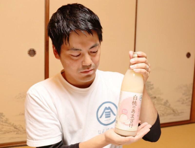 規格外の白桃を使って開発した甘酒を手にする難波さん