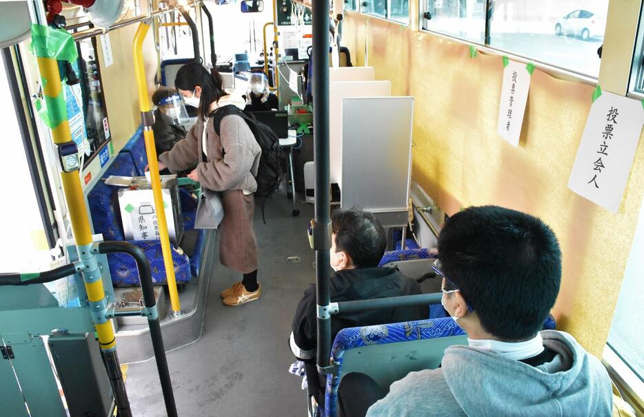 路線バスの車内で投票する大学生（左）＝山口県下関市の下関市立大学で2022年1月24日、大坪菜々美撮影