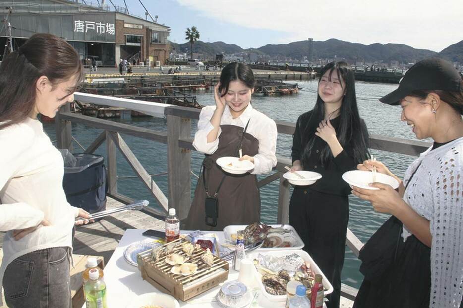 唐戸市場で取り扱う魚介類で浜焼き体験を楽しむ人たち＝5日、下関市唐戸町